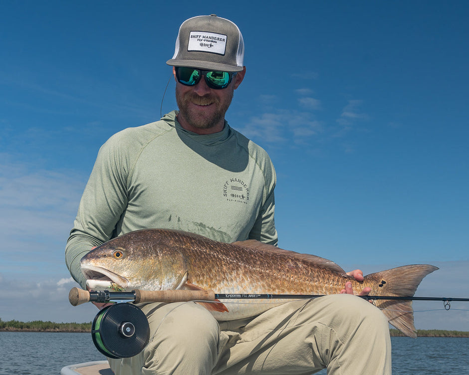Man holding a large fish on a boat with a clear blue sky in the background