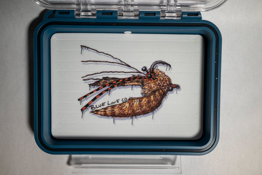 A clear plastic fly box with a blue trim, featuring a crab pattern illustration on the lid.
