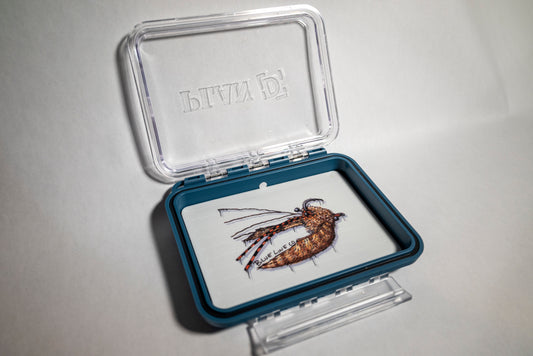 A clear plastic fly box with a blue trim, featuring a crab pattern illustration on the lid.