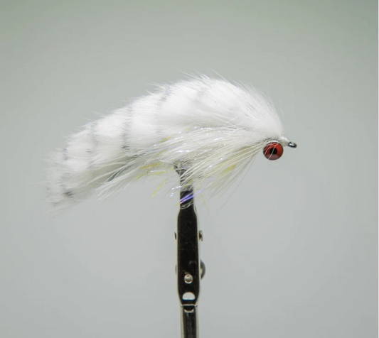 Fishing fly with white and yellow feathers on a gray background. rabbits foot white
